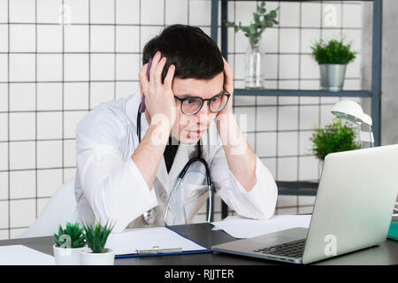 Emotion with young doctor being exhausted in a hospital Stock Photo