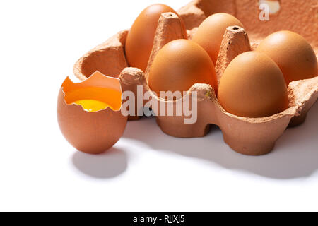 six eggs in packaging mould box with one broken egg in front, isolated on white background, clipping-path included Stock Photo