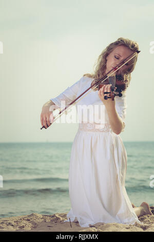 Woman playing violin by sea at beach Stock Photo - Alamy