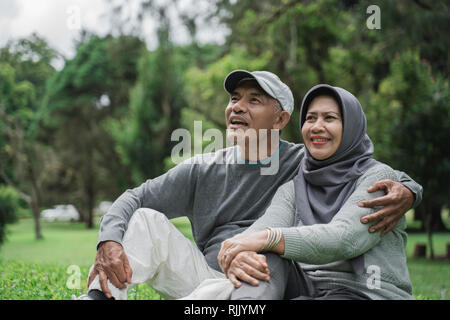 mature old man and woman sitting on a grass in the park Stock Photo