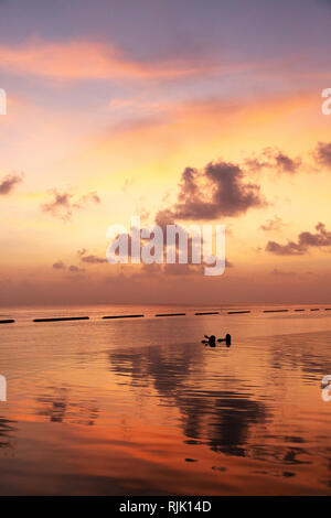 Maldives travel - A couple watching a dramatic colourful sunset over Rasdhoo atoll, the Maldives, Asia Stock Photo