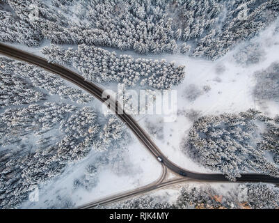 Aerial view of road in the middle of the forest with two cars. Winter season Stock Photo