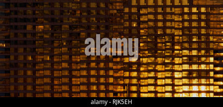 Close-up of building windows reflecting warm sunset light in an abstract geometric facade pattern. Stock Photo