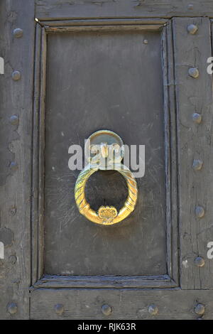 Yellow brass door handle knob. On vintage wood; decorative old metal door handle knocker. Stock Photo