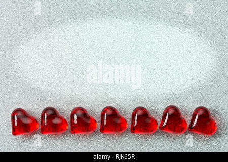 Valentine, wedding card background with a row of shiny hearts lying on their sides on a silver brocade background Stock Photo