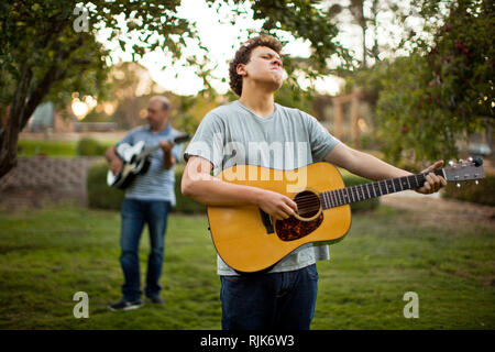 Father and son practicing playing guitar together. Stock Photo