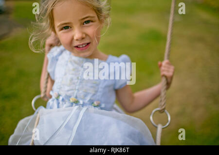 Portrait of a little girl playing on a swing in the back garden. Stock Photo