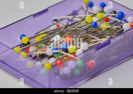 close up macro on colorful pin head needles for sewing in a violet plastic box Stock Photo