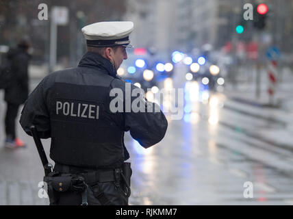 07 February 2019, Hessen, Frankfurt/Main: In the pouring rain, a policeman secures the passage of President Steinmeier's motorcade. In the context of non-public meetings, the Federal President exchanged views with police officers on their everyday lives. Photo: Boris Roessler/dpa Stock Photo