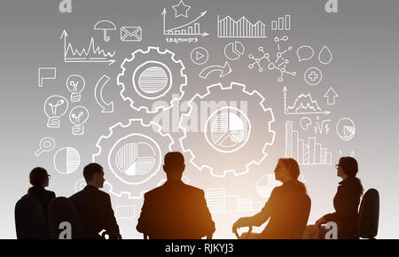 Silhouettes of business people sitting at table and workingn at strategy Stock Photo