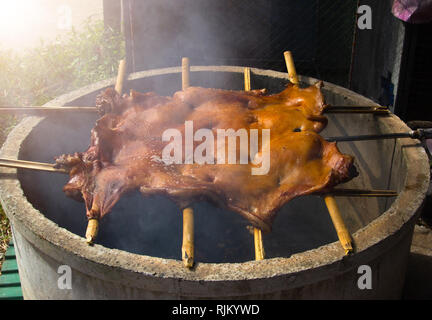 Grill the pig with a grilling on the grill. Grilled traditional coal and fire. Stock Photo