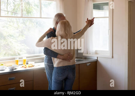 Aged couple husband and wife dancing in the kitchen Stock Photo
