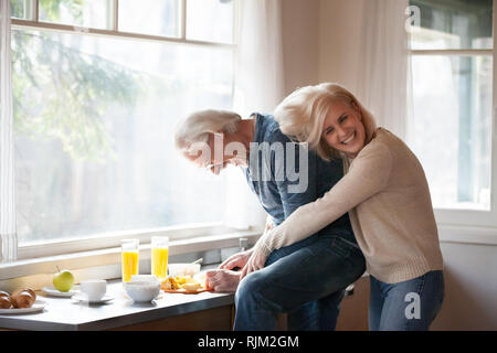 Funny aged mature couple having fun during cooking Stock Photo