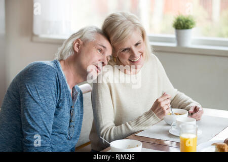 Mature married couple sitting dreaming together at dining table Stock Photo
