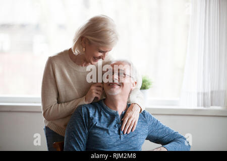 Wife leaned over to her husband hugging him from behind Stock Photo