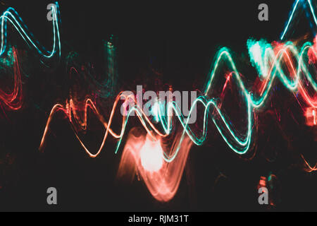 Colorful red and turquoise glowing wavy lines on black backdrop.  Stock Photo