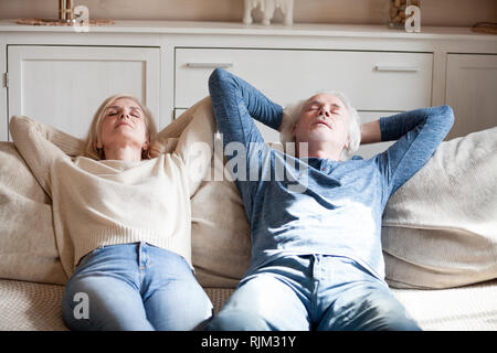 Mature spouses lying on couch putting hands behind head Stock Photo
