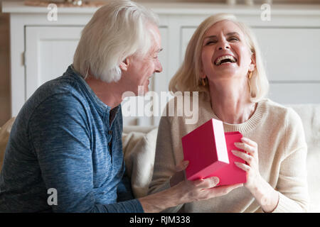 Spouses celebrating anniversary sitting in living room at home Stock Photo