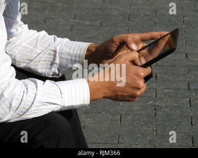 Digital tablet in male hands close-up, man in office suit sitting on the street with tablet PC. Concept of businessman, official, online communication Stock Photo