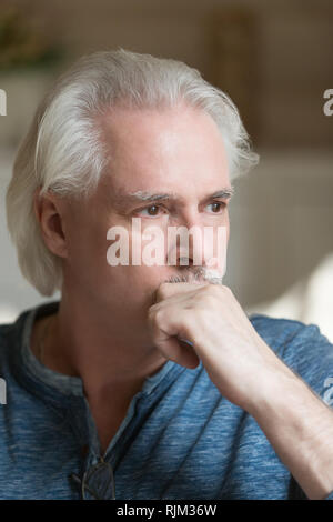 Focused puzzled grey haired man at home Stock Photo