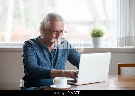Serious mature man working on computer at home Stock Photo
