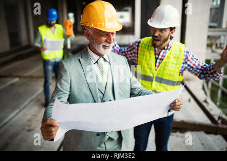 Engineer, foreman and worker discussing in building construction site Stock Photo