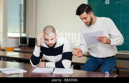 Young guy sitting at classroom worried because of difficulties with studies Stock Photo