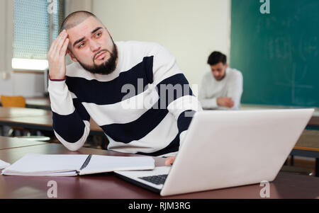 Portrait of male university student sitting at desk and focused on his project Stock Photo