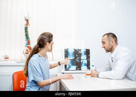 Young woman during the medical consultation with senior therapist looking on the tomography print at the office Stock Photo