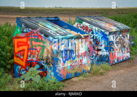 A couple of industrial dumpsters covered in neon colored graffiti from spray paint by tourists on roadside near Cadillac Ranch in Amarillo, TX Stock Photo