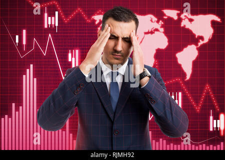 Broker man touching painful temples with both hands as stress gesture caused by economic crisis and financial decline on graph Stock Photo