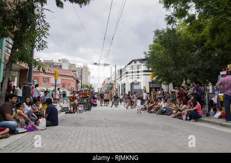 Busker in Cordoba's hip neighbourhood Paseo de las Artes playing street music on guitar and vocals to crowds of people sitting on the curbs Stock Photo