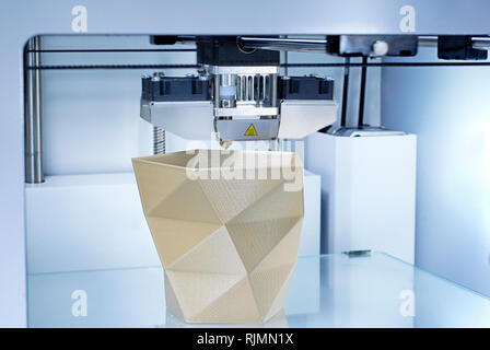 3D Printer producing a Vase from golden PLA (Polylatic Acid) with additive manufacturing technique. Symbol for Future Project Industry or Industry 4.0 Stock Photo