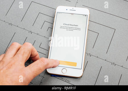 PARIS, FRANCE - SEP 26, 2016: Male hand holding New Apple iPhone 7 8 Plus smartphone after unboxing and testing by installing the app application software iCloud Keychain security password access Stock Photo
