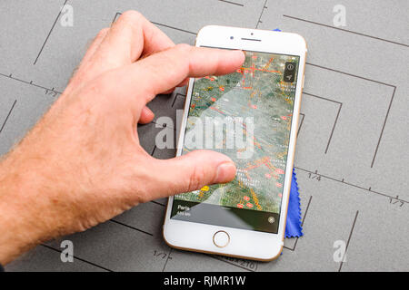 PARIS, FRANCE - SEP 26, 2016: Male hand holding New Apple iPhone 7 8 Plus smartphone after unboxing and testing by installing the app application software Apple Maps GPS flyover Paris France Stock Photo