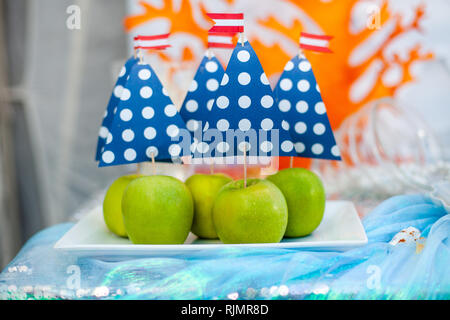 Green apples with blue paper sail. Sea time theme on the party's candy bar. Stock Photo