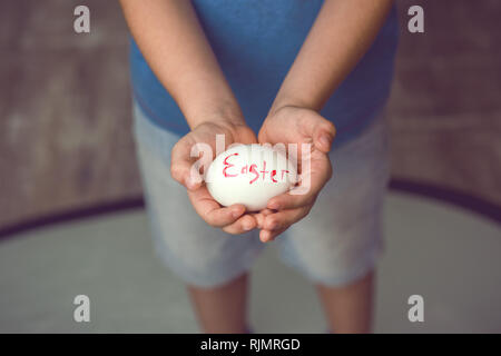 Eggs with the inscription Happy Easter the child holds in her hands in front of him. Stock Photo