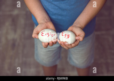 Eggs with the inscription Happy Easter the child holds in her hands in front of him. Stock Photo