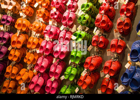 NEW YORK CITY, USA - JUL 17, 2010: Crocs soft rubber children sandals hanging on a rack display for sale. Colourful sandals of diverse colours blue, r Stock Photo