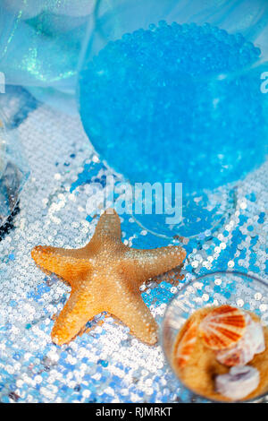 Bright blue balls in the glass vase and dried yellow sea starfish. Sea time theme on the party's candy bar. Stock Photo
