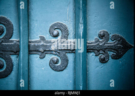 Old vintage and rusty black iron door ornament arrow on heavy and massive antique style blue wood door. Stock Photo
