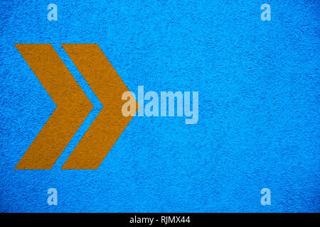 Yellow orange arrows signs pointing right direction over intense bright blue color stucco rough wall as an empty rustic and simple background texture  Stock Photo