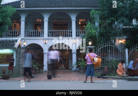 Caption: Luang Prabang, Laos - Sep 2002. Locals waiting to give alms to monks during the ritual morning collection outside the Villa Santi Hotel, an o Stock Photo