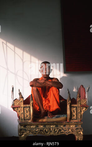 An elderly monk relaxing on his throne at Wat Pha Mahathat in Luang Prabang. Stock Photo