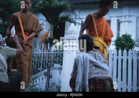 Caption: Luang Prabang, Laos - Sep 2003. Ladies are giving alms to novice monks in the early hours of the morning, Luang Prabang. Supported by the com Stock Photo