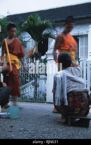 Caption: Luang Prabang, Laos - Sep 2003. Ladies are giving alms to novice monks in the early hours of the morning, Luang Prabang. Supported by the com Stock Photo