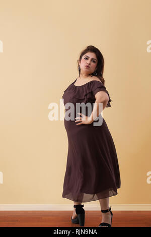 Fat woman in a long brown dress dancing on high heels Stock Photo