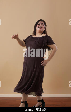 Fat woman in a long brown dress dancing on high heels Stock Photo