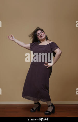 Fat woman in a long brown dress dancing on high heels Stock Photo