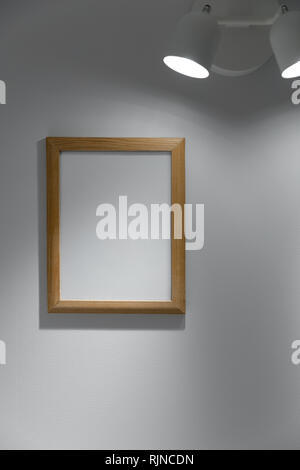 blank wooden picture frame hanging on the wall under the lamp Stock Photo